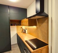 A kitchen in a 3-room apartment with a wooden decor floor and dark cabinets.