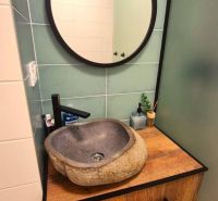 A bathroom in a 3-room apartment with a stone sink and a wooden decor floor.