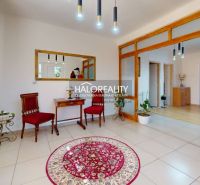 Interior of a family house with red armchairs, a table, and a round carpet.