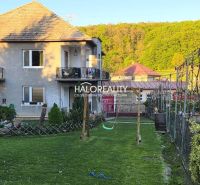 A family house in Poltár with a balcony, garden, and swing, surrounded by greenery.