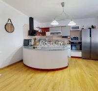 The kitchen in the family house with a wooden decor floor is dominated by white cabinets and appliances.