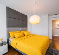 Bedroom in a 3-room apartment with a wooden decor floor and yellow bedding.