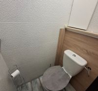 A toilet with a wooden decor on the floor in a 3-room apartment.
