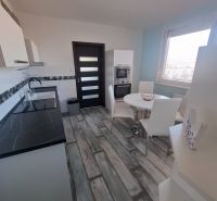 A kitchen with a sophisticated black and white unit and a dining table, 3-room apartment.