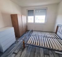 A bedroom with a bed, wardrobe, and wooden decor flooring in a three-room apartment.