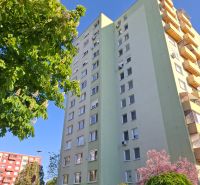A view of the apartment building near B. Němcová in Nové Zámky, surrounded by greenery and cars.