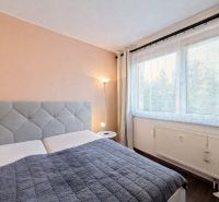 A bedroom in a 4-room apartment with an upholstered headboard and a lamp next to the window.