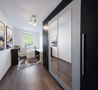A room in a 4-room apartment with a wooden decor floor, a mirrored wardrobe, and decorations.