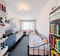 Children's room in a 4-room apartment with beds, colorful books, and decorative wallpaper.