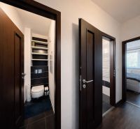 A hallway in a 4-room apartment with a wooden decor floor, leading to the toilet and bedroom.