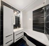 A bathroom with white cabinets and black tiles in a 4-room apartment.
