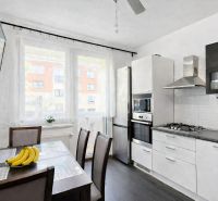 A kitchen in a 4-room apartment with a dining table and appliances, flooring with a wooden decor.