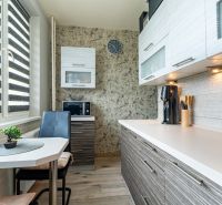 A kitchen in a 2-room apartment with a microwave, brown cabinets, and a table with chairs.