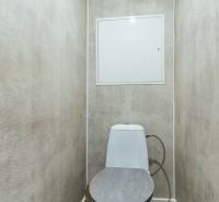 A toilet with a WC bowl and walls with a light texture, 2-room apartment.