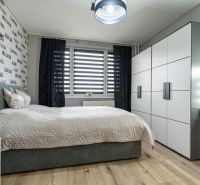 Bedroom in a 2-room apartment with a bed, wardrobe, and floor with wooden decor.