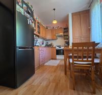 A kitchen in a 2-room apartment with a wooden decor floor and wooden furniture.