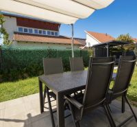 The garden of a family house in Rajka with a terrace, table, chairs, and lawn.