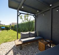 The garden of a family house in Rajka with a seating area under a pergola and a swing.