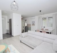 Living room in a family house with a sofa, dining table, and wooden decor flooring.