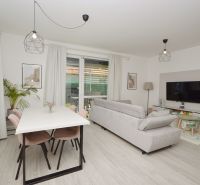 A family house with a wooden decor floor, a sofa, a table, and a television.