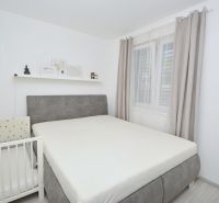 Bedroom in a family house with a double bed, a crib, and decorations on the shelf.