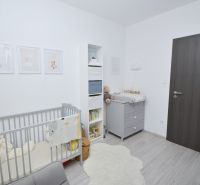 Children's room with a crib, changing table, and wooden decor flooring in a family house.