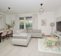 Living room in a family house with a wooden decor floor, a cozy couch, and a gaming corner.