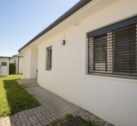 A family house in Rajka with a lawn, paving, and modern shutters.