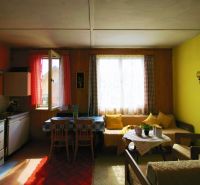 A room in a cottage with wooden decor, afternoon light through the curtains on the window.