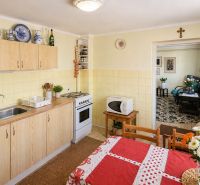 A kitchen in a family house with a dining table, flowers, and kitchen furniture with a wooden decor.
