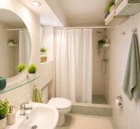 Bathroom in a family house with a sink, mirror, shower corner, and curtain.