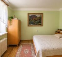 Bedroom in a family house with a painting, wooden furniture, and a floor with a wooden decor.
