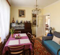Living room in a family house with flowers on the windowsill and an impressive chandelier.