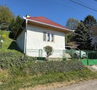 A family house in Čaradice with a red roof and green gates in the garden.