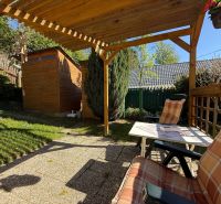 A garden at a family house in Čaradice with a pergola and a wooden cottage.