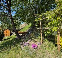 The garden of a family house in Čaradice with a gazebo and a wooden house on a grassy area.
