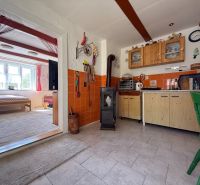 A kitchen in a family house with a stove and a passage to a bright living room.