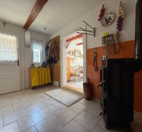 Interior of a family house with a tiled stove, wooden decor flooring, and a hanging storage system.