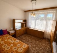 A room with a bed and a wardrobe in a 3-room apartment with a floral carpet.