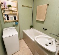 Bathroom with a bathtub, washing machine, and a shelf with containers in a 3-room apartment.