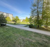 Grassy area with a sidewalk and apartment buildings on Tulská Street in Zvolen.