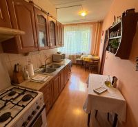 A kitchen in a 3-room apartment with a wooden decor floor, equipped with a gas stove.