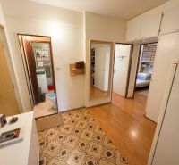 The hallway in a 3-room apartment with a wooden decor floor and entrance to the bathroom.