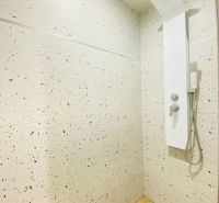 A bathroom with a shower and a wooden decor floor in a 2-room apartment.