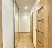 A hallway in a 2-room apartment with a wooden decor floor and built-in wardrobes.