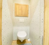 Toilet room in a 2-room apartment with wood-patterned tiles and flooring.
