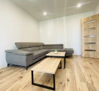 Living room in a two-room apartment with a corner sofa and a floor with a wooden decor.