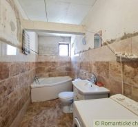 A bathroom in a family house with a bathtub and a washing machine, tiled with ceramic tiles.