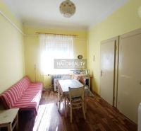 Interior of a 2-room apartment with a wooden decor floor, dining table, and sofa.
