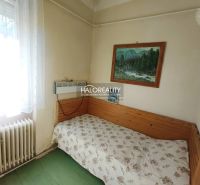 A simple room in a 2-room apartment with a bed, a picture, and a window with a radiator.